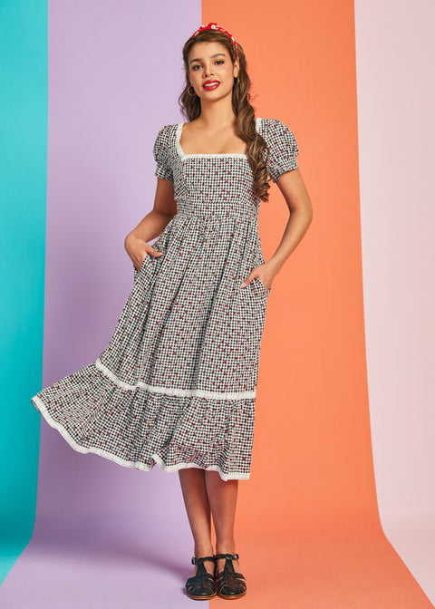 Woman twirling in vintage-inspired strawberry gingham midi dress with pockets