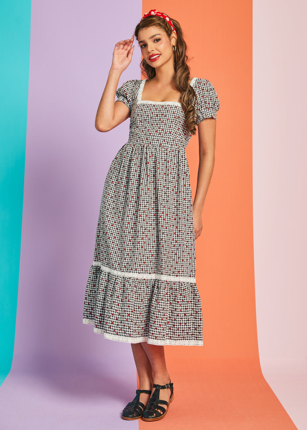 Woman wearing black and white gingham strawberry print midi dress with puff sleeves and square neckline