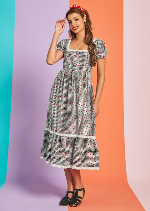 Woman wearing black and white gingham strawberry print midi dress with puff sleeves and square neckline