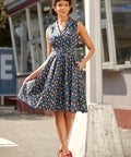 Woman wearing a sleeveless dress with a colorful chicken print and fit-and-flare silhouette.