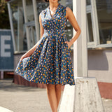 Woman wearing a sleeveless dress with a colorful chicken print and fit-and-flare silhouette.