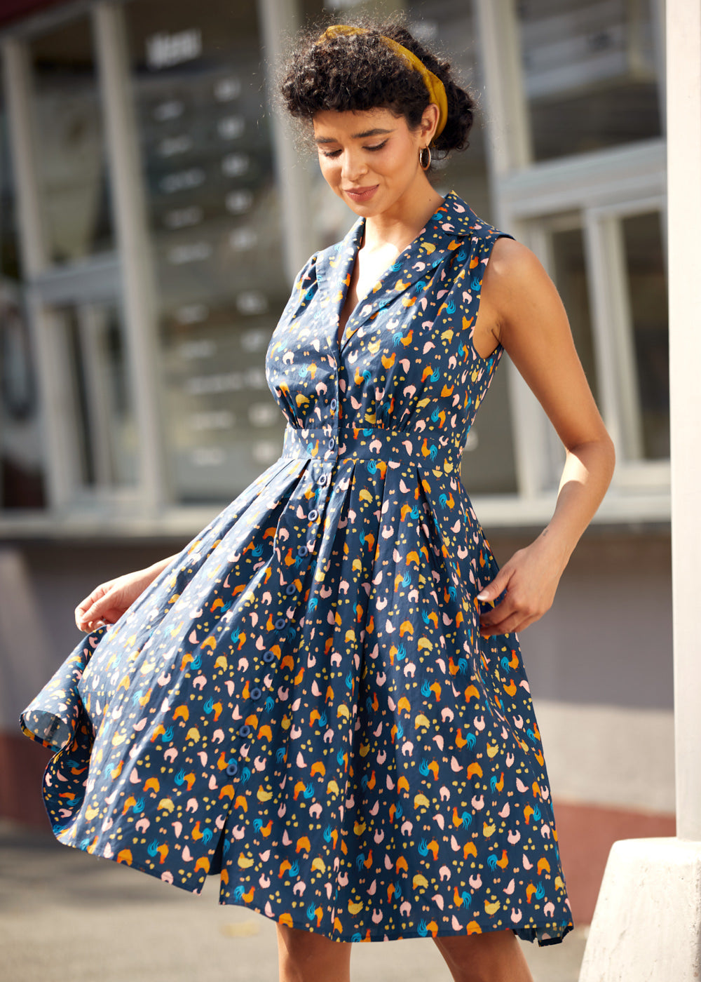 Woman twirling in a sleeveless fit-and-flare dress with playful chicken print.