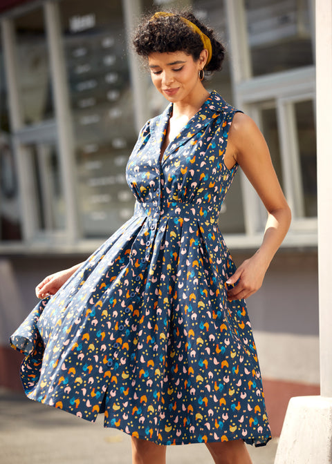 Woman twirling in a sleeveless fit-and-flare dress with playful chicken print.