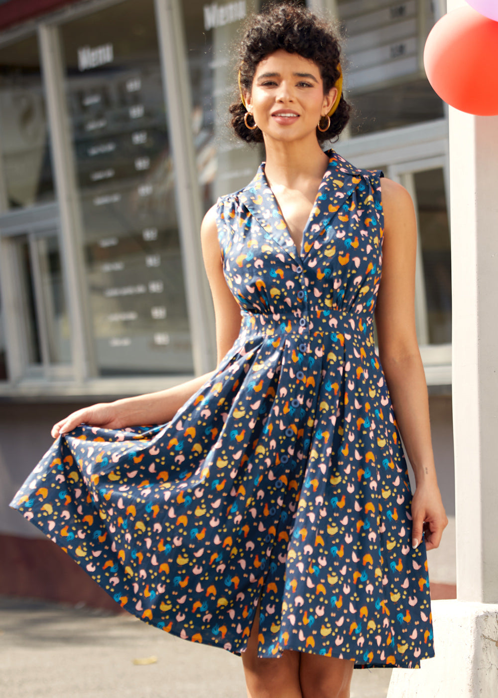 Woman wearing vintage-inspired chicken print cotton dress with pockets and retro-inspired styling.