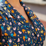 Close-up of the notched collar and button-front detail on a navy blue cotton dress.