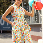 Woman in a colorful vegetable print dress holding balloons outdoors.