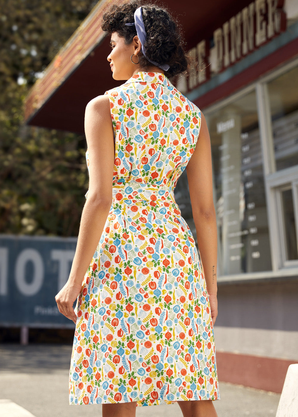 Back view of a sleeveless fit-and-flare cotton dress with collared neckline and vegetable print.