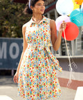 Woman styling a retro cotton shirt dress with colorful produce print for a sunny summer outing.