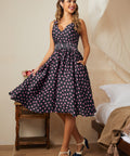 Woman wearing a polka dot dress in a bedroom setting with high heel shoes