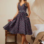 Woman wearing a polka dot dress in a bedroom setting with high heel shoes