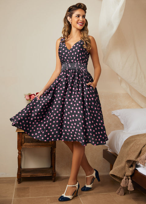 Woman wearing a polka dot dress in a bedroom setting with high heel shoes