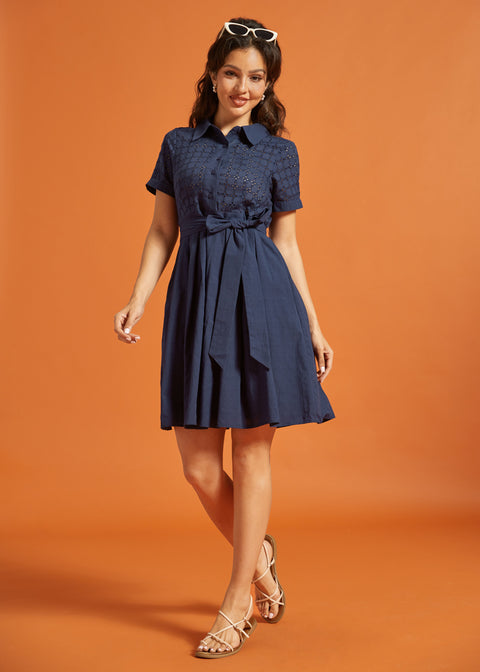 Full-length view of a navy cotton fit-and-flare dress with an eyelet bodice, collared neckline, and gathered skirt.