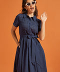 Woman wearing a retro-inspired fit-and-flare dress with an eyelet upper, smooth skirt, and side pockets.