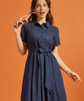 Woman wearing a vintage-inspired navy shirt dress with an embroidered eyelet top and full skirt.