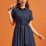 Woman wearing a vintage-inspired navy shirt dress with an embroidered eyelet top and full skirt.