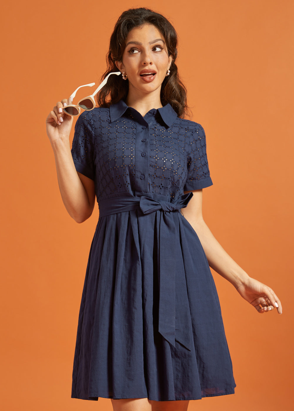 Woman wearing a vintage-inspired navy shirt dress with an embroidered eyelet top and full skirt.