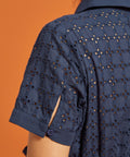 Close-up of the eyelet-embroidered short sleeve with cuff and button-tab slit detail.