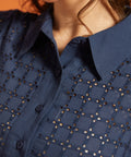 Close-up of the pointed collar, button-front placket, and eyelet-embroidered bodice.