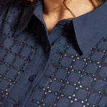 Close-up of the pointed collar, button-front placket, and eyelet-embroidered bodice.