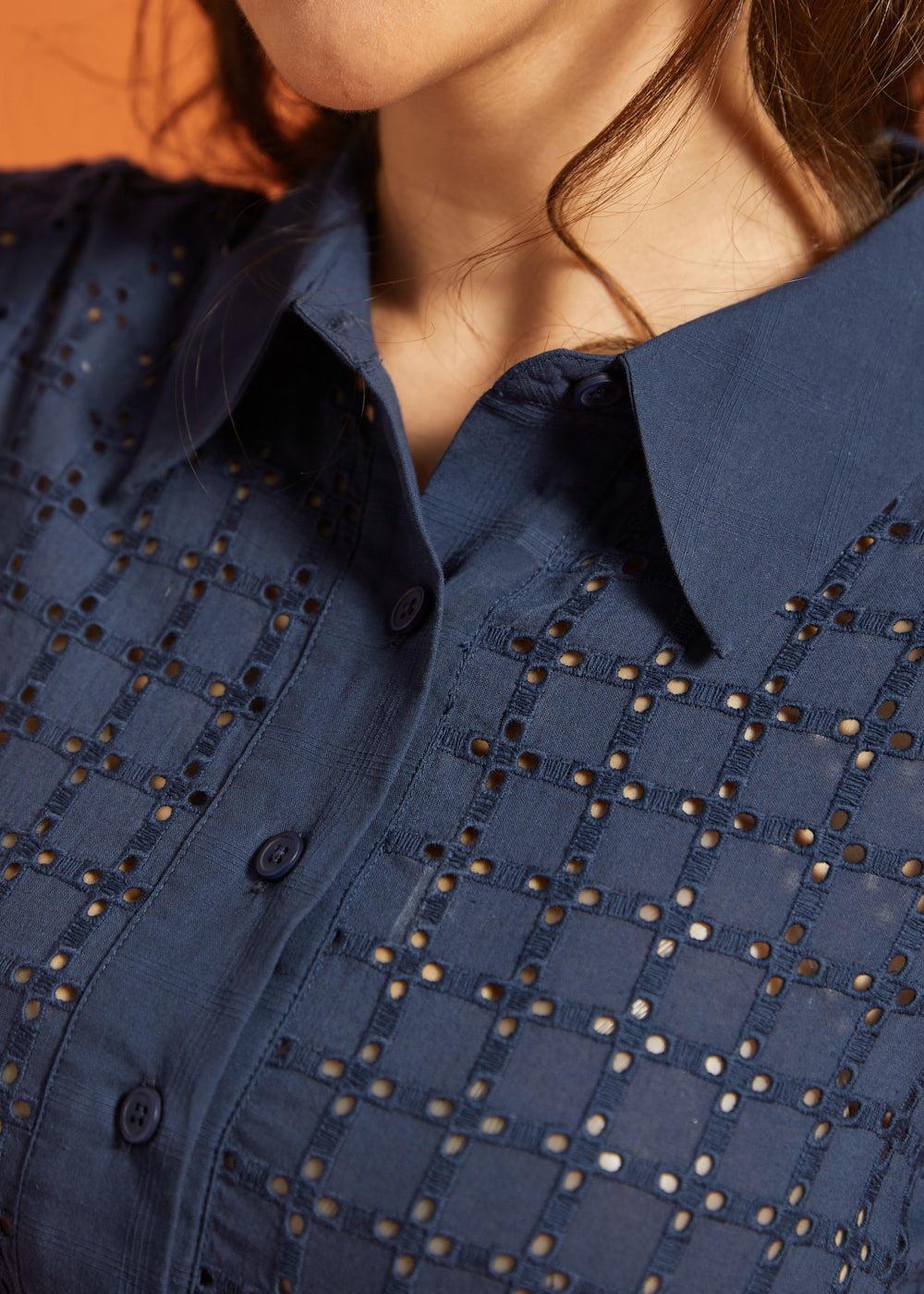 Close-up of the pointed collar, button-front placket, and eyelet-embroidered bodice.