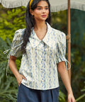 Woman wearing the Dear Diary Blouse in Blue Willow, a vintage-inspired cotton blouse with an oversized pointed collar and covered buttons.