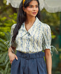 Vintage-inspired women's cotton blouse featuring a statement collar, covered button front, and romantic puff sleeves.
