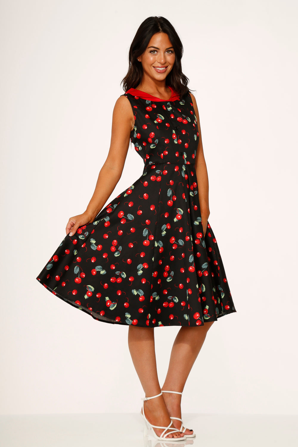 Woman wearing a black dress with red cherry pattern on a white background