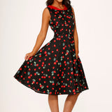 Woman wearing a black dress with red cherry pattern on a white background