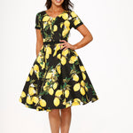 Woman wearing a black dress with yellow lemon print on a white background
