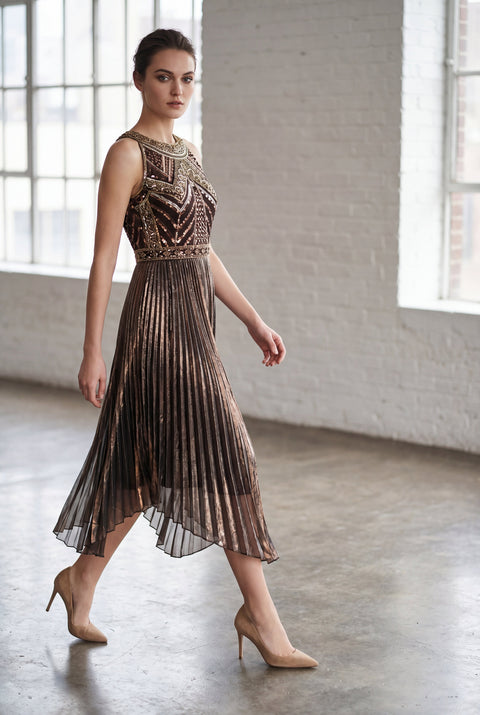Woman wearing a metallic dress in a room with large windows and white brick walls.