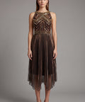 Woman wearing a gold flapper dress with intricate detailing on a gray background