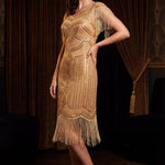 Woman wearing a gold sequin dress with fringe in a dimly lit room.