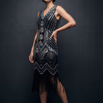 Woman wearing a black and silver beaded flapper dress against a dark background