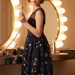 Woman wearing an embroidered floral fit-and-flare dress with illusion mesh neckline and layered tulle skirt.