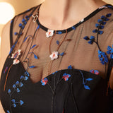 Close-up of the illusion mesh neckline with intricate blue floral embroidery and butterfly accents on a party dress.