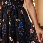 Close-up of the embroidered black tulle skirt featuring intricate blue, blush, and ivory floral embroidery.