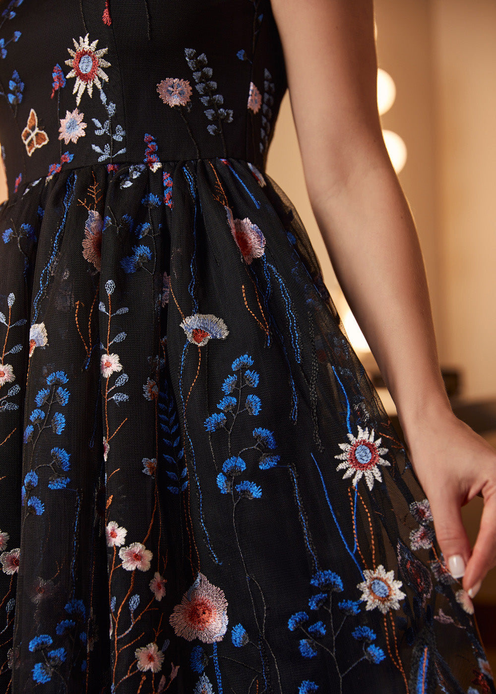 Close-up of the embroidered black tulle skirt featuring intricate blue, blush, and ivory floral embroidery.