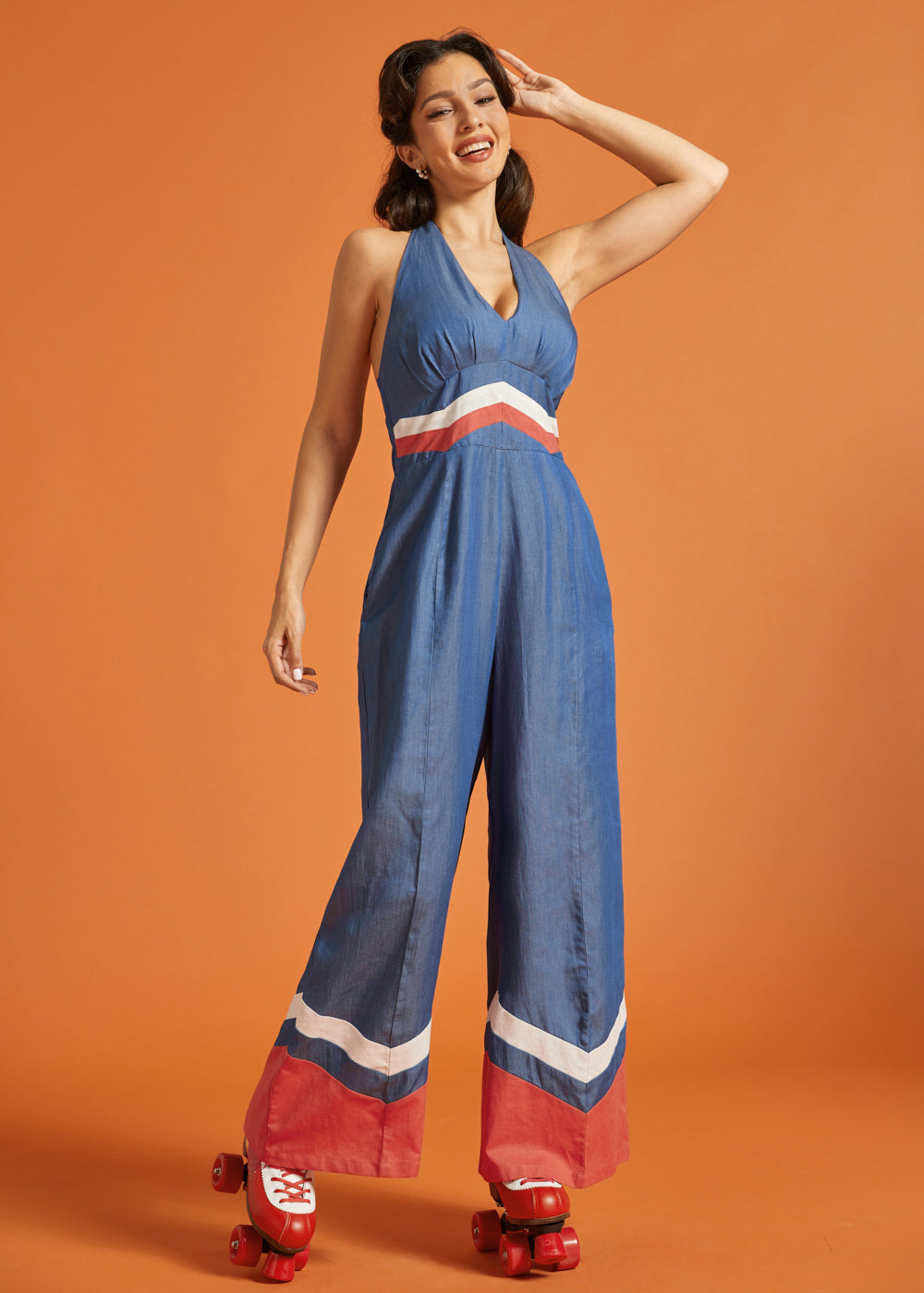 Woman roller skating in a retro-inspired wide-leg halter jumpsuit with bold color-block accents.