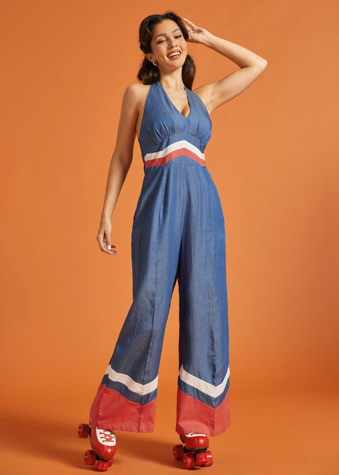 Woman roller skating in a retro-inspired wide-leg halter jumpsuit with bold color-block accents.