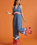 Woman wearing a retro blue jumpsuit with halter tie neckline and wide-leg silhouette.