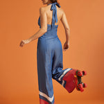 Back view of a woman wearing a halter jumpsuit with adjustable tie and smocked elastic back.