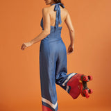 Back view of a woman wearing a halter jumpsuit with adjustable tie and smocked elastic back.