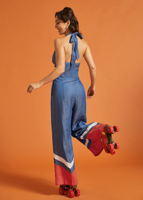 Back view of a woman wearing a halter jumpsuit with adjustable tie and smocked elastic back.