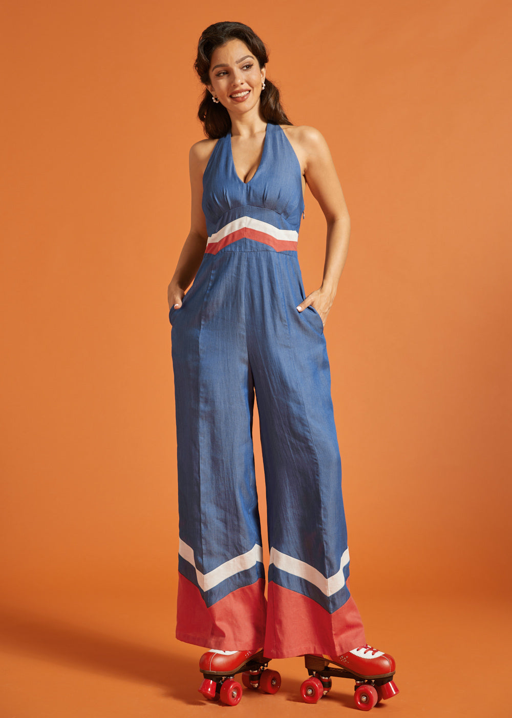 Woman posing in a vintage-inspired wide-leg jumpsuit with side pockets and chevron trim.
