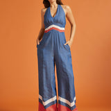 Woman posing in a vintage-inspired wide-leg jumpsuit with side pockets and chevron trim.
