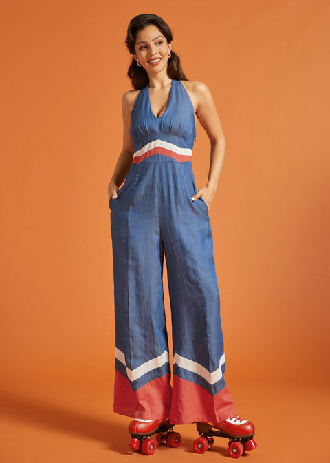 Woman posing in a vintage-inspired wide-leg jumpsuit with side pockets and chevron trim.