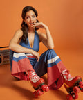 Woman sitting in a wide-leg halter jumpsuit with vintage color-block accents.