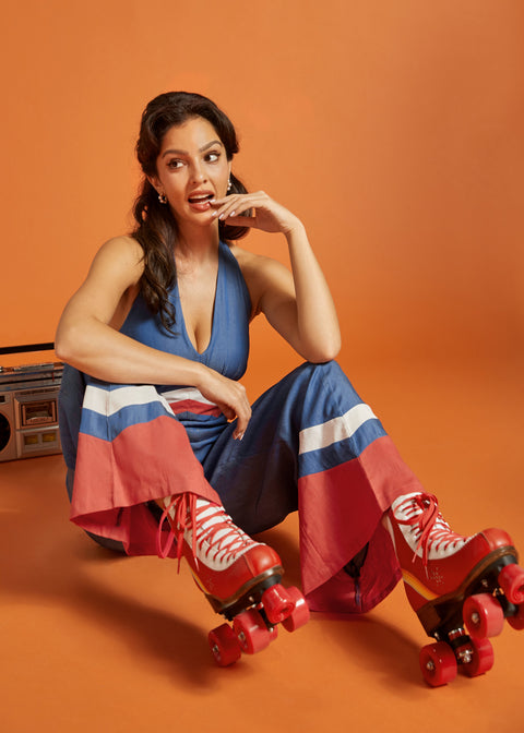 Woman sitting in a wide-leg halter jumpsuit with vintage color-block accents.