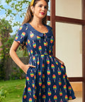 Woman wearing a navy dress with colorful popsicle pattern outdoors.