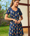 Woman wearing a navy dress with colorful ice cream pattern outdoors.
